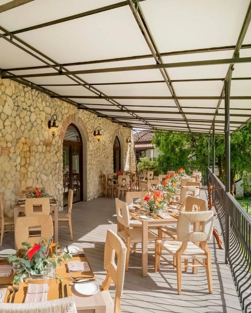 Tables set with flowers on the covered stone terrace of the Terra restaurant